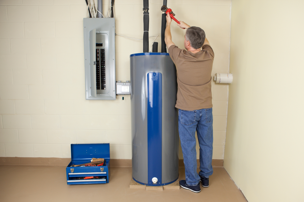 Wendig technician tightening a pipe fitting on a residential water heater