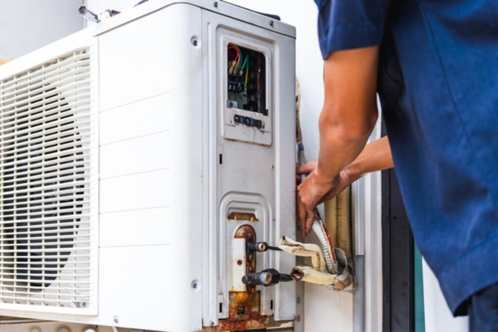 Technician working on the refrigerant connections of an outdoor AC unit